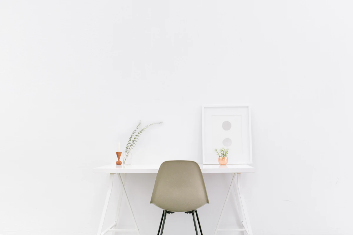 Minimal white desk with a chair and a small plant