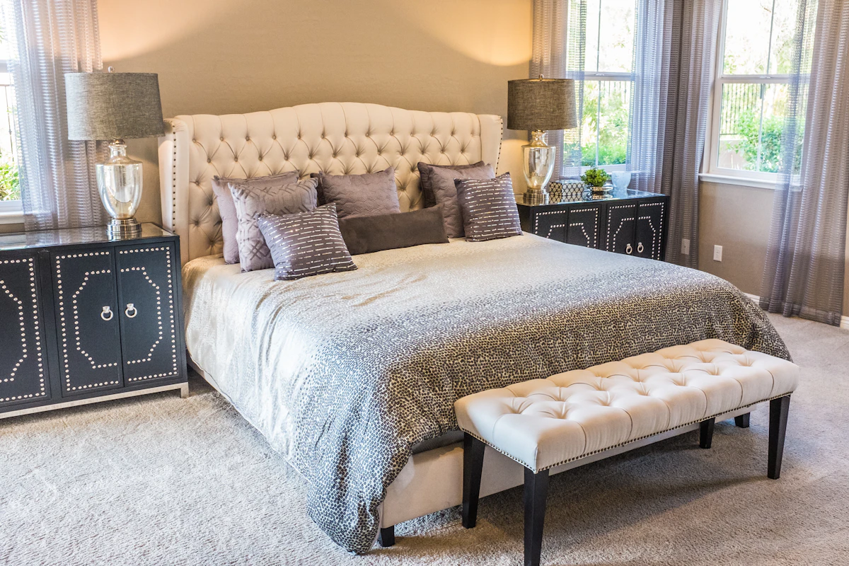 Bedroom with bedside lamps, upholstered bed and daylight from two windows