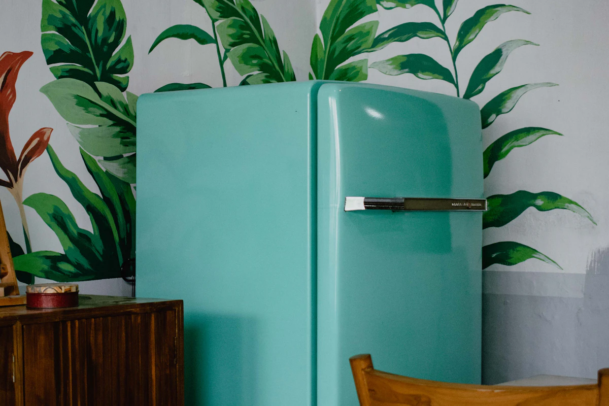 Green refrigerator and freezer surrounded by indoor plants