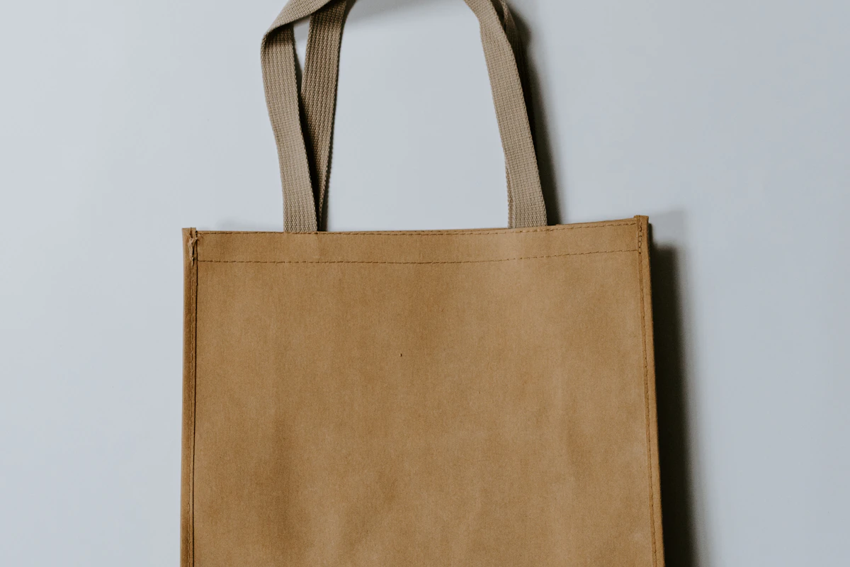 Brown reusable tote bag hanging against a light wall