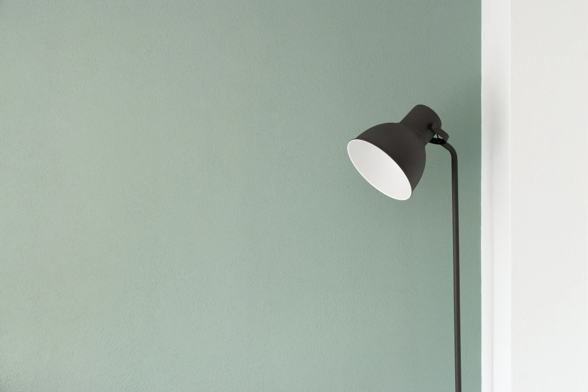 Black adjustable reading lamp against a pale green wall